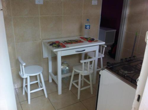 a small kitchen with a white table and two stools at Apartamento em Santos in Santos