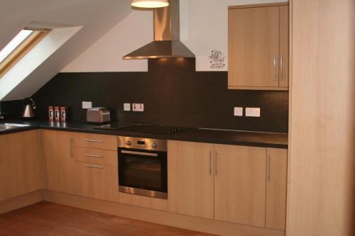 a kitchen with wooden cabinets and a stove top oven at Mulberry in Nairn