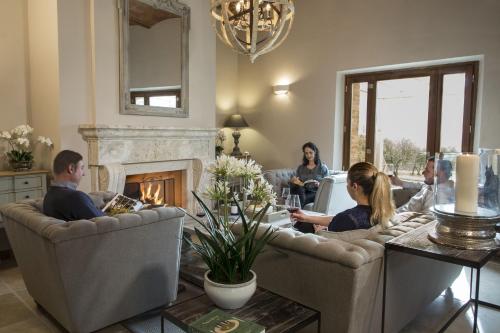 a group of people sitting in a living room with a fireplace at Borgo Argiano in Castelnuovo Berardenga