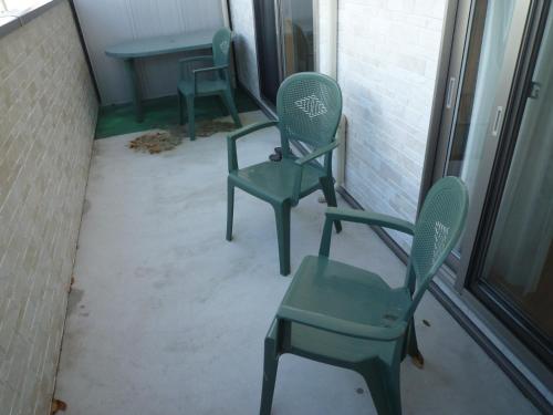 two green chairs and a table on a porch at Sea Side Hostel Light House in Onomichi