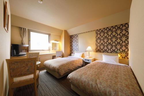 a hotel room with two beds and a television at Kanazawa Central Hotel Annex in Kanazawa