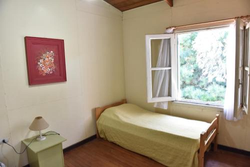 a small bedroom with a bed and a window at Los Arrayanes in Tandil