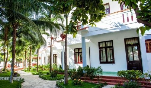 a white building with palm trees in front of it at Muine Pacific Resort in Mui Ne