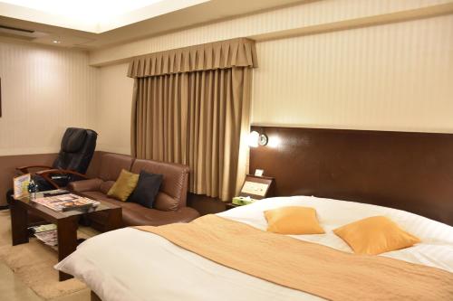 ein Hotelzimmer mit einem Bett und einem Sofa in der Unterkunft Hotel Coco de Palms & Mer (Love Hotel) in Ōita