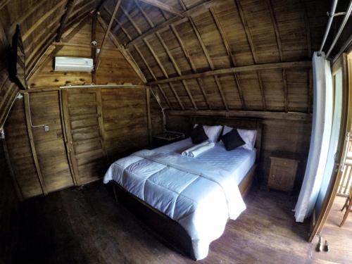 a bedroom with a bed in a wooden house at Beautiful house in Nusa Penida
