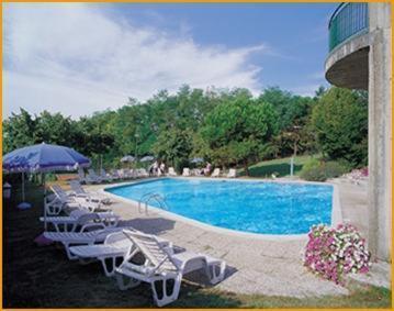a swimming pool with lounge chairs and an umbrella at Park Hotel Galileo in Reggello