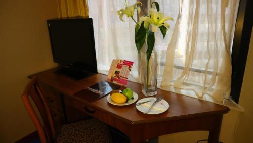 a table topped with a plate of fruit and a vase of flowers at The Kimberley Hotel in Hong Kong