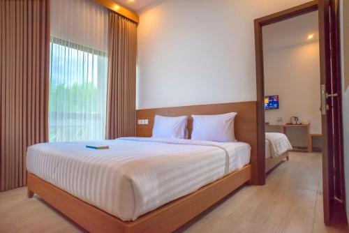 a bedroom with a large bed and a large window at Java Village Resort by HOMEE Yogyakarta in Yogyakarta