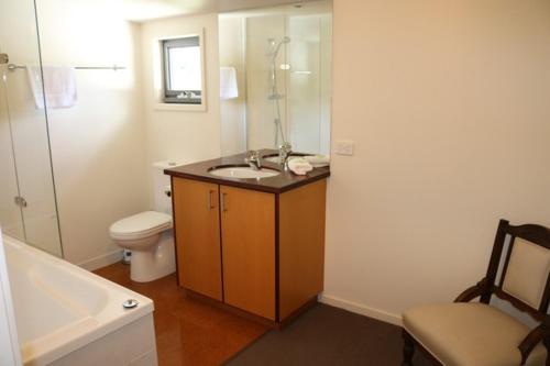 a bathroom with a sink and a toilet and a bath tub at Bright Woodlands Retreat in Bright