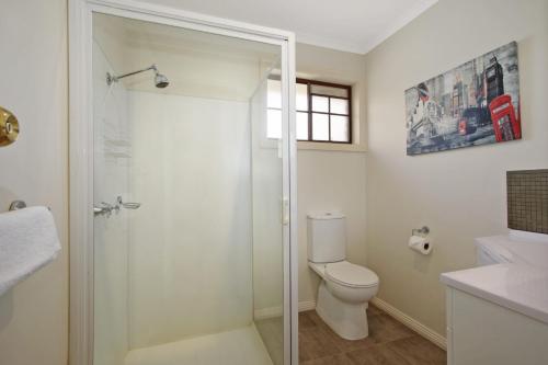 a bathroom with a toilet and a glass shower at Oak Cottage - Tudor Village Unit 5 in Bright