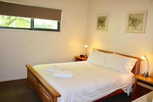 a bedroom with a large white bed with a window at Bright Woodlands Retreat in Bright