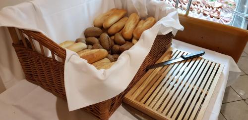 Una canasta de bagels en un mostrador con un cuchillo. en Hotel Diana, en Nové Mesto nad Váhom