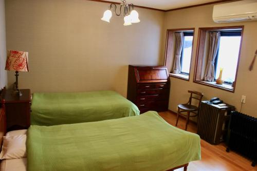 a bedroom with two beds and a dresser and windows at Spa Lodge Redwood Inn in Takayama