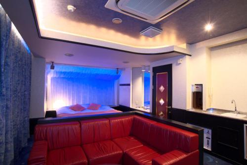um sofá vermelho num quarto com uma cama em Hotel Coco de Annex (Love Hotel) em Kitakyushu