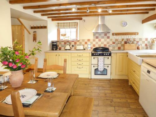 a kitchen with a wooden table and a stove at Fell View Cottage in Bootle