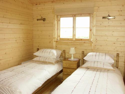 LivertonにあるThornlea Log Cabinのウッドルーム ベッド2台 窓付