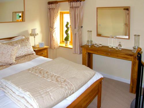 a bedroom with a bed and a dresser and a mirror at Howle Hideaway in Walford
