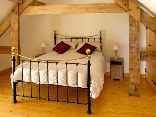 a bedroom with a large bed with white sheets and red pillows at Nuffies Cottage in Elton