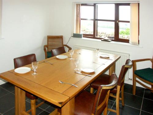 een eettafel met stoelen en een grote houten tafel bij Penrallt Cottage in Y Felinheli