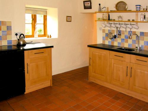 une cuisine avec des placards en bois et un comptoir noir dans l'établissement Pen y Parc, à Meliden