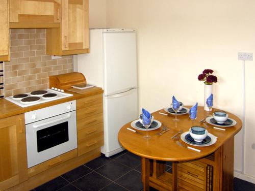 a kitchen with a table and a white refrigerator at 1 Mirehouse Place in Angle