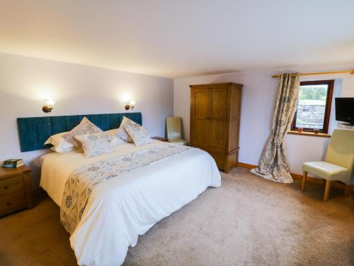 a bedroom with a large white bed and a chair at Hazelwood Cottage in Ingleton