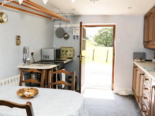eine Küche mit einem Tisch und einer offenen Tür in der Unterkunft Undercragg in Seathwaite