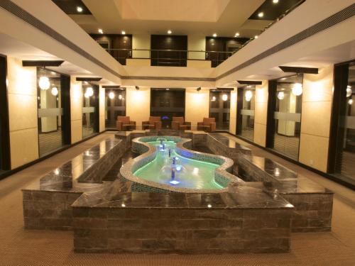 een lobby met een zwembad in het midden van een gebouw bij The Cambay Grand in Ahmedabad