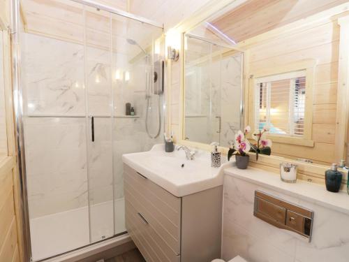 biała łazienka z umywalką i prysznicem w obiekcie Old Joiners Shop w mieście Staithes