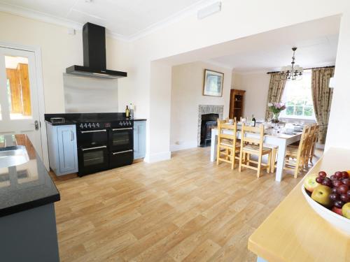 a kitchen and dining room with black appliances and wooden floors at Dolau Farmhouse in Llanwnen