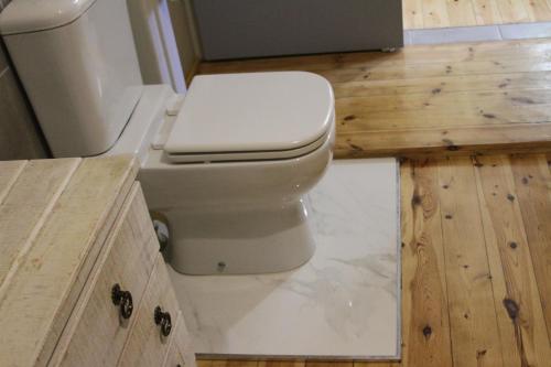 a bathroom with a toilet and a wooden floor at Ripple Hill Hotel in Patensie