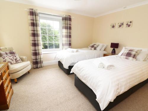 a bedroom with two beds and a chair and a window at Dolau Farmhouse in Llanwnen