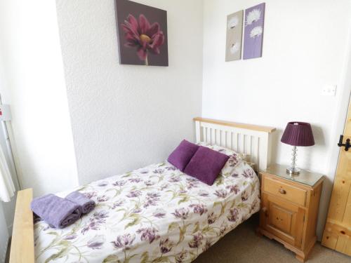 a bedroom with a bed with purple pillows and a table at Black Horse Cottage in Settle