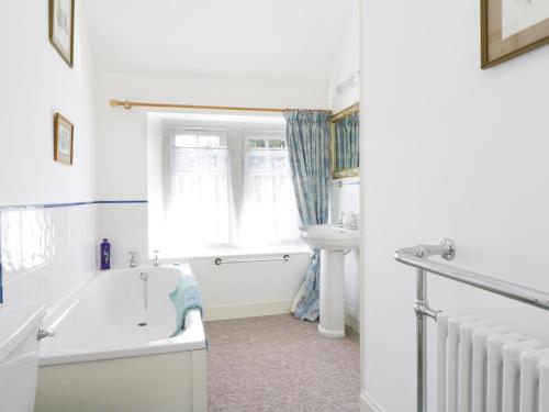 a white bathroom with a tub and a sink at Bannatyne Lodge in Newtyle