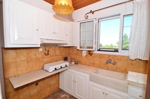 eine Küche mit weißen Schränken, einem Waschbecken und Fenstern in der Unterkunft Fiore Hill Sea View Studios in Vasilikos