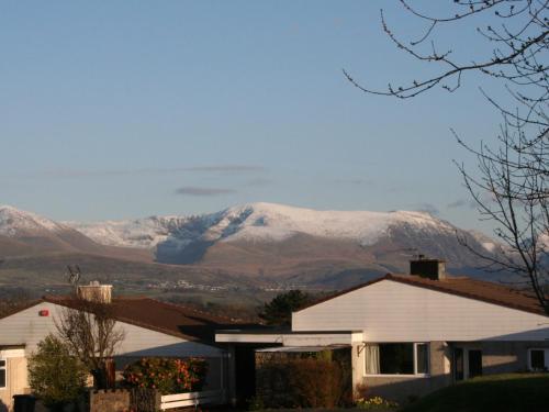 a snow covered mountain in the distance with houses at Anglesey White Haven in Llandegfan