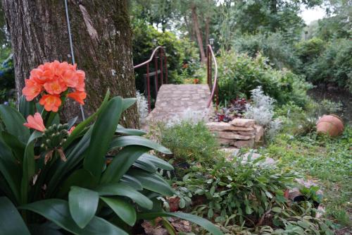 a garden with flowers and a tree and a staircase at Le Moulin du Bignon in Lassy