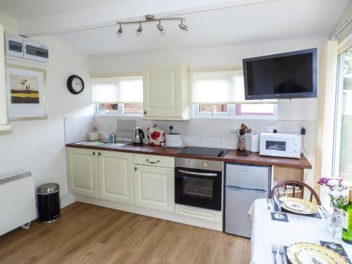 a kitchen with white cabinets and a microwave at River's Nook in Llangynog