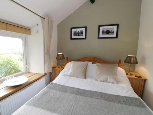 a bedroom with a white bed and a window at Ty Cynon in Blaenau-Ffestiniog