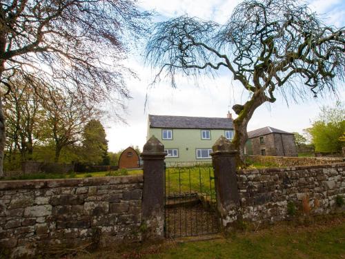 a house behind a stone wall with a gate at Westmains Farm in Penton