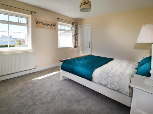 a bedroom with a bed and two windows at Anglesey White Haven in Llandegfan