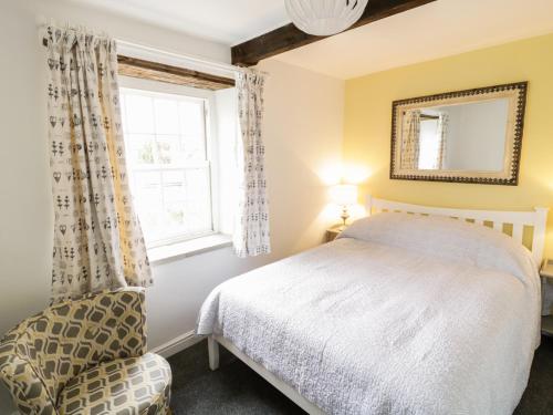 een slaapkamer met een bed, een stoel en een raam bij Olive Cottage in Richmond