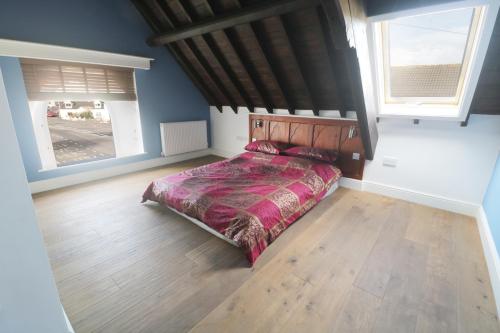 a bedroom with a bed and two windows at No 1 Church Cottages in Llanelli