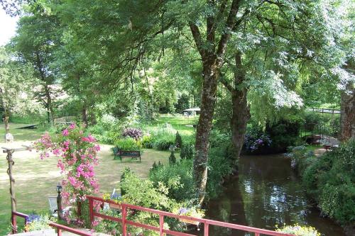 a garden with a fence and a river with flowers at Le Moulin du Bignon in Lassy
