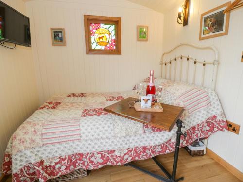 The Clydes في Tremeirchion: غرفة نوم مع سرير وطاولة مع زجاجة من النبيذ