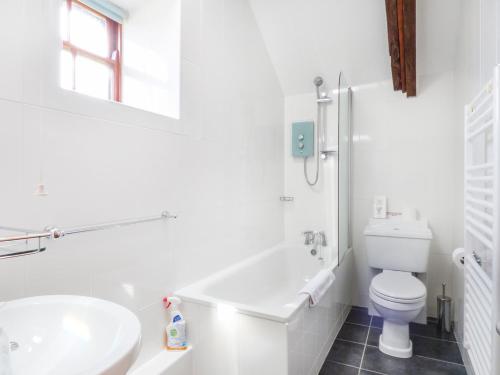 a white bathroom with a toilet and a sink at The Bullshed in Saint Erth