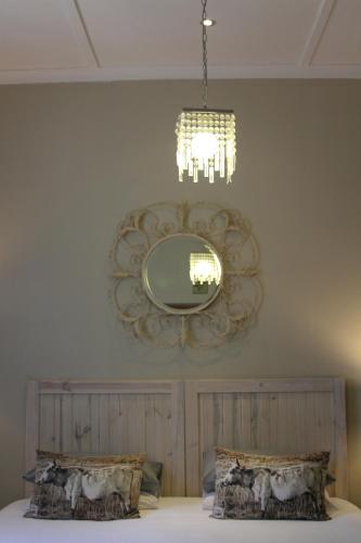 a mirror on the wall above a bed with pillows at Ripple Hill Hotel in Patensie