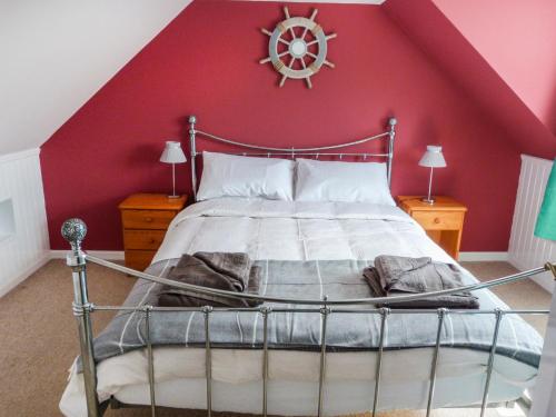 um quarto com uma cama com uma parede vermelha em 5 Distillery Cottages em Whitehills