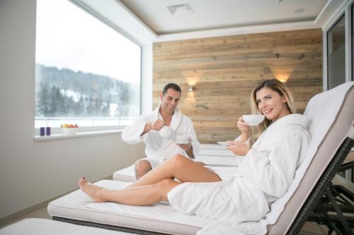 a man and woman sitting on a bed in a bath room at R&R Residenzen HOTEL in Mitterbach