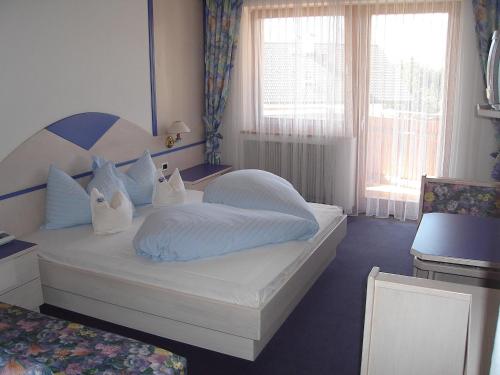 sypialnia z łóżkiem z białą pościelą i poduszkami w obiekcie Sporthotel Rasen w mieście Rasun di Sotto